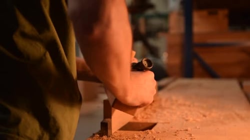 Man Smoothing Wood with Hand Plane in Workshop