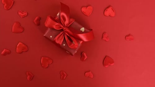 Gift with Heart Decorations on Red Background