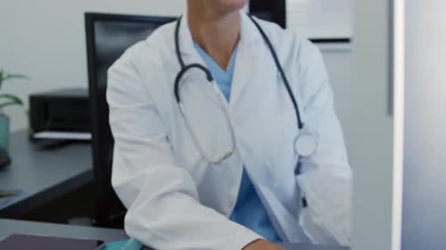 Female Doctor Smiling and Typing at Desk