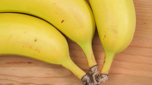 Close Up of Three Yellow Bananas on Wood