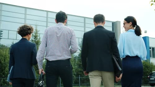 Back View of Group of Young Businesspeople Walking To Office Center Talking