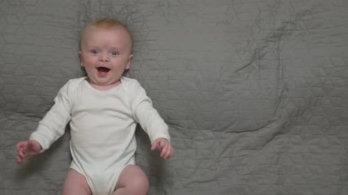 Smiling Baby Lying on Gray Blanket