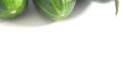 Cucumbers with Water Droplets on White Surface