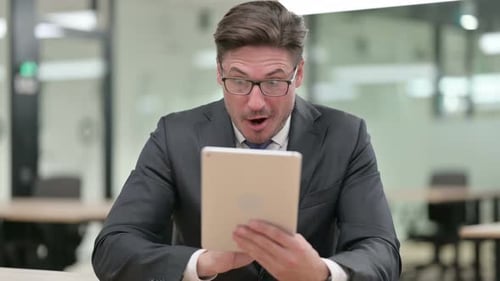 Happy Businessman Receiving Good News on Tablet
