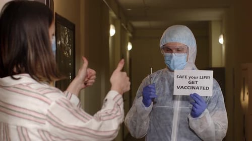 Hazmat Suited Man Holding Vaccine Sign Visiting Woman
