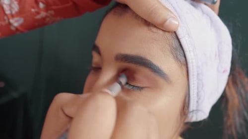 Close up of young woman's eyes and make up artist putting eye shadow on her eyes