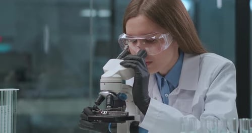 Scientist Examining Sample Through Microscope in Modern Lab