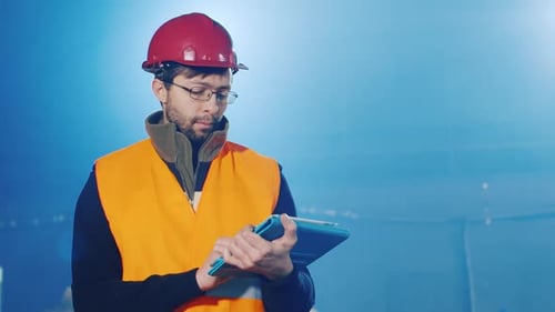 The Ingineer Works in a Warehouse Uses a Tablet