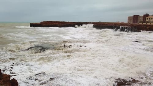 Slow Motion of a Strong and Powerful Sea Wave Crashing Against a Rocky Shore with Large Rocks.
