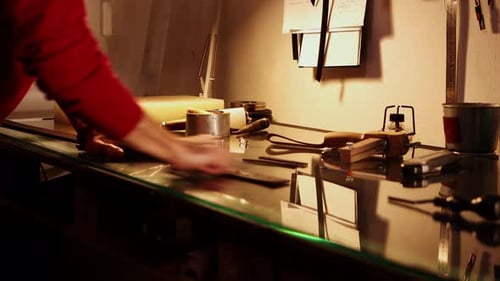 Ein Mann poliert in seiner persönlichen Werkstatt ein Stück Leder für den Gürtel