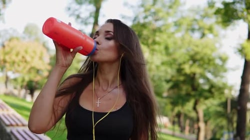 Athletic Woman Drinking Water in Park