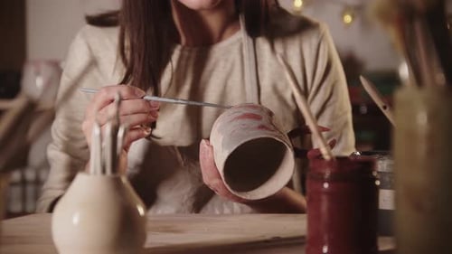 Woman Painting Ceramic Mug in Pottery Studio
