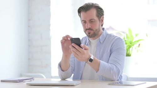 Junger Mann benutzt Smartphone im Büro