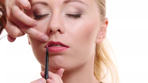Maskenbildner trägt Lipgloss auf Modellippen auf