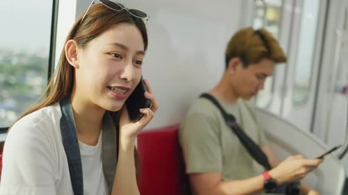 Asiatische Frau entspannt sich auf dem Zugsitz, während sie die Smartphone-App benutzt