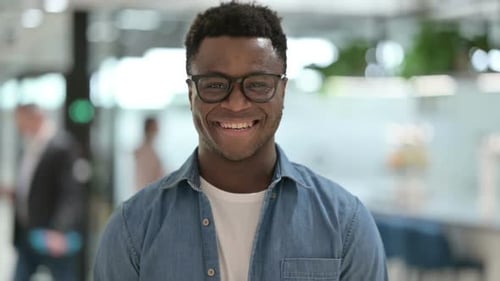 Man Smiling in Office Wearing Glasses and Denim