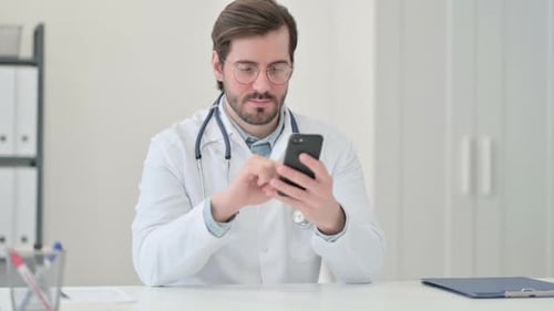 Male Doctor Using Smartphone in Bright Office