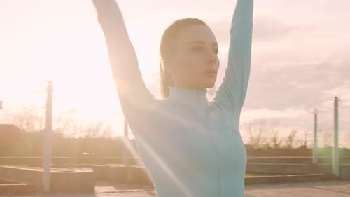 Athletic Woman Warming Up on Rooftop at Sunset