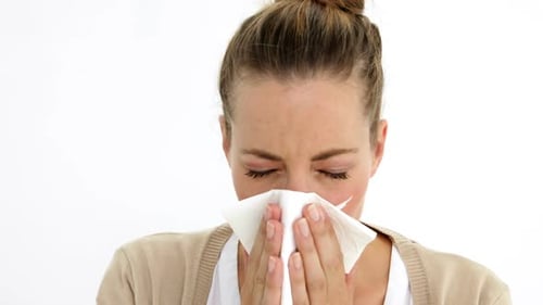 Woman Blowing Nose with Tissue Against White Background