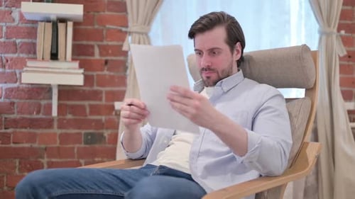 Man Angrily Reading Documents in a Rocking Chair