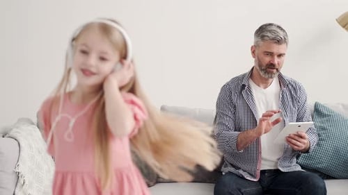 Girl Dances as Father Uses Tablet at Home