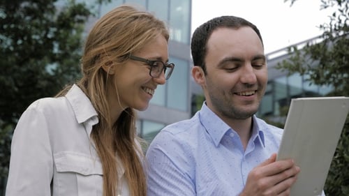 Woman and Man Collaborating Using Tablet Outdoors