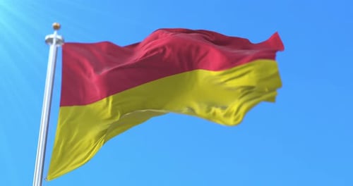 Realistic Waving Red and Yellow Flag Against Blue Sky Loop