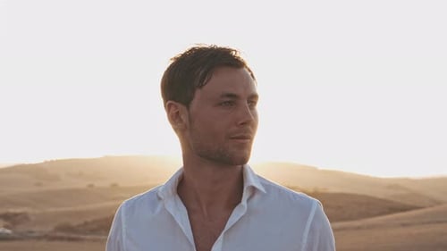 Sol brilhante e homem bonito apreciando a vista do campo de trigo aberto