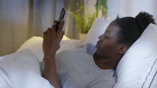 Woman Using Cellphone While Lying in Bed