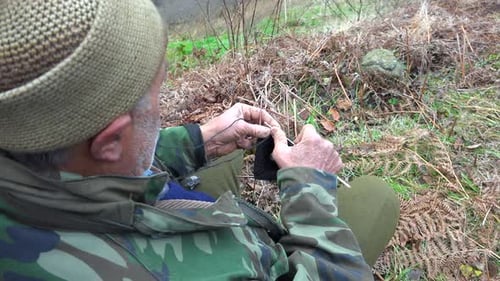 Man Knitting Black Yarn Outdoors in Rural Setting