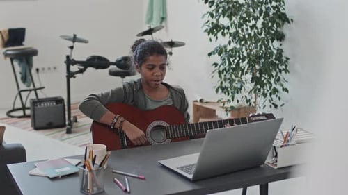 Teen Learning Guitar Online in Sunny Home