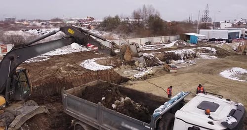 Aerial Top View Yellow Excavator Pouring Soil Into Tipper