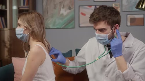 Doctor Listening to the Lungs of Young Woman Wearing Medical Masks Consultation and Vaccination