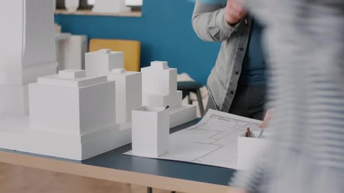 Close Up of Architect Taking Notes on Blueprints Plan to Work on Building Model and Maquette