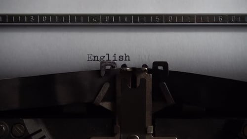 Typing word English on retro typewriter. Close up.