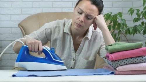 Tired Woman Ironing Clothes at Home