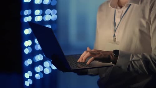 Adult Types on Laptop in Front of Glowing Lights