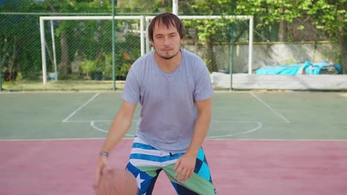 Man Dribbling Basketball on Outdoor Urban Court