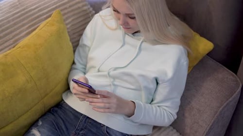 Young Woman Using Smartphone on Couch Indoors