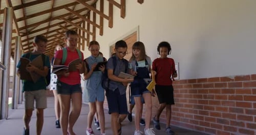 Group of kids with books walking in the school corridor