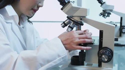 Scientist Examining Sample Through Microscope in Lab