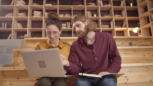 Two Colleagues Collaborate on Laptop in Modern Office