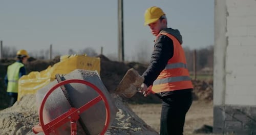 Männlicher Arbeiter legt Zement auf Baustelle in Mischer