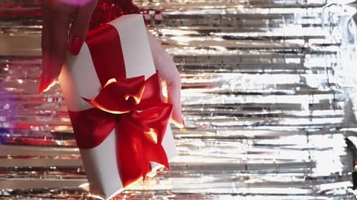 Wrapped Gift with Red Ribbon Held in Hands