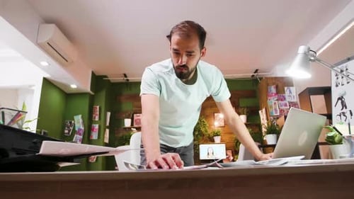 Bearded Man Working on Laptop in Modern Office