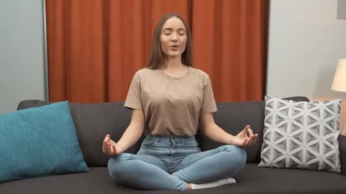 Woman Meditating on Couch Indoors