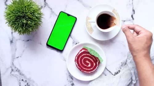 Top View of Smart Phone Tea and a Cake on Tiles Background