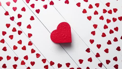 Vlentine's Day Composition. Heart Shaped Sequins Placed on White Wooden Table