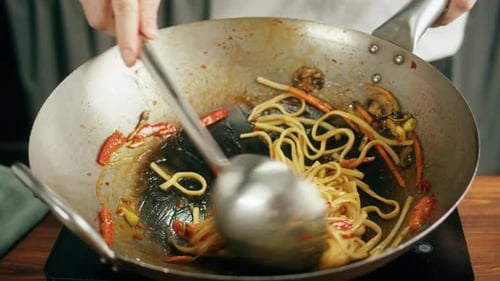 Chef Prepares Stir Fry in Wok with Ladle