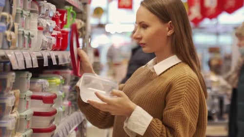 A Woman Chooses New Plastic Containers for Storing Food in a Supermarket